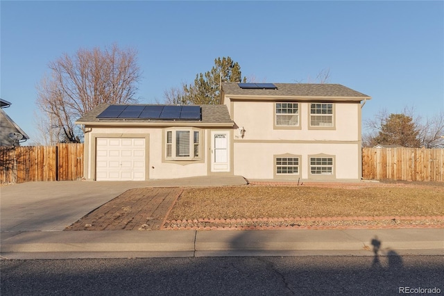 tri-level home featuring a garage and solar panels