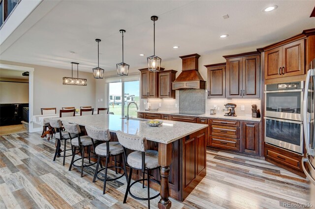3308 County Road 19, Fort Lupton, CO 80621 - kitchen featuring custom range hood, double oven, a sink, black electric stovetop, and a kitchen breakfast bar