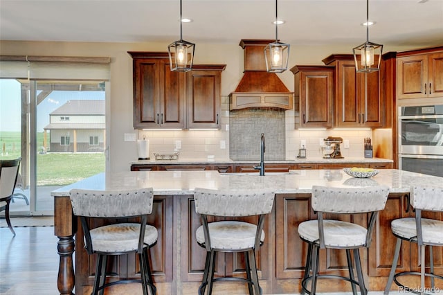 3308 County Road 19, Fort Lupton, CO 80621 - kitchen featuring stainless steel double oven, tasteful backsplash, light stone counters, light wood-style floors, and pendant lighting