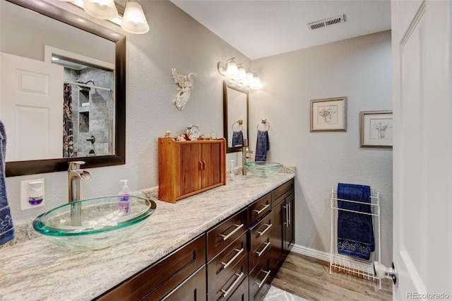 3308 County Road 19, Fort Lupton, CO 80621 - bathroom with double vanity, wood finished floors, tiled shower, heating unit, and baseboards