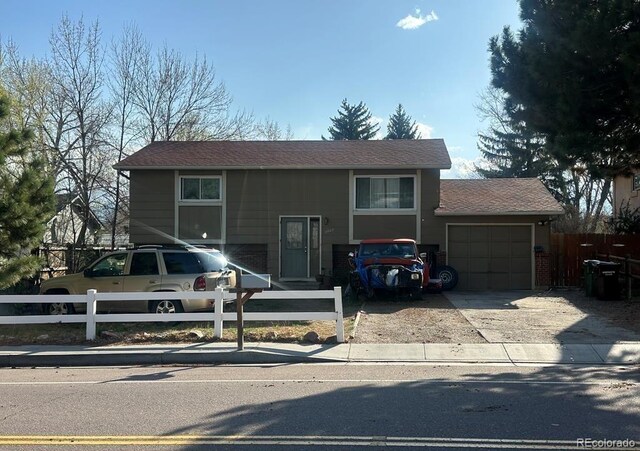 raised ranch with fence, concrete driveway, and an attached garage