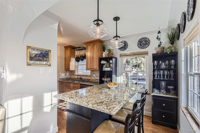 kitchen with wood-type flooring, sink, pendant lighting, and a kitchen bar