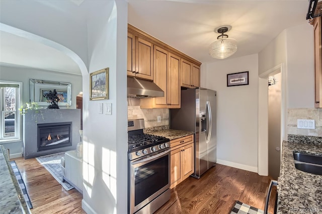 kitchen featuring appliances with stainless steel finishes, dark hardwood / wood-style floors, and dark stone countertops