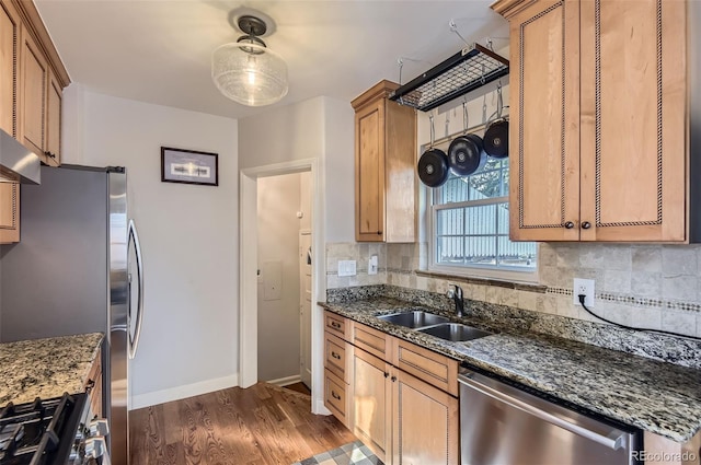 kitchen with appliances with stainless steel finishes, tasteful backsplash, sink, dark stone counters, and dark wood-type flooring