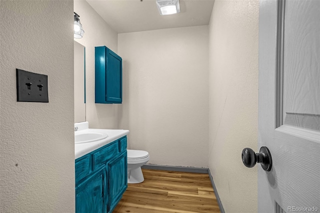 86 Will Stutley Dr, Divide, CO 80814 - half bathroom featuring wood finished floors, toilet, vanity, a textured wall, and baseboards