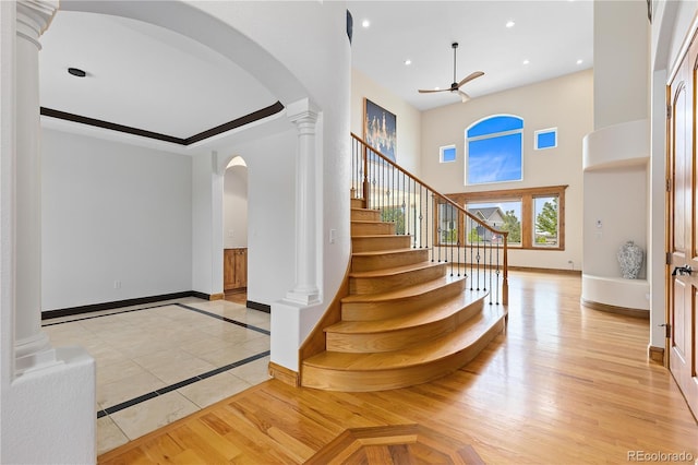 entryway with decorative columns, baseboards, arched walkways, light wood-style floors, and recessed lighting