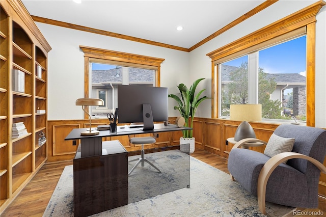 office area with ornamental molding, light wood finished floors, and wainscoting