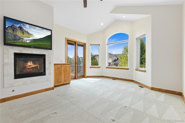 unfurnished living room with light carpet, visible vents, baseboards, a tiled fireplace, and lofted ceiling