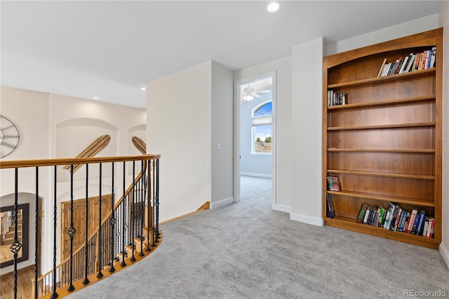 corridor featuring light carpet, baseboards, built in features, and recessed lighting