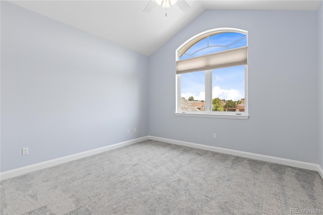 carpeted spare room with vaulted ceiling, ceiling fan, and baseboards