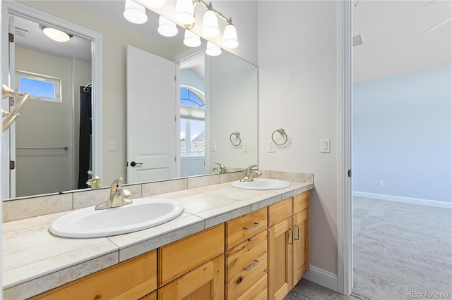 full bathroom featuring double vanity, baseboards, and a sink