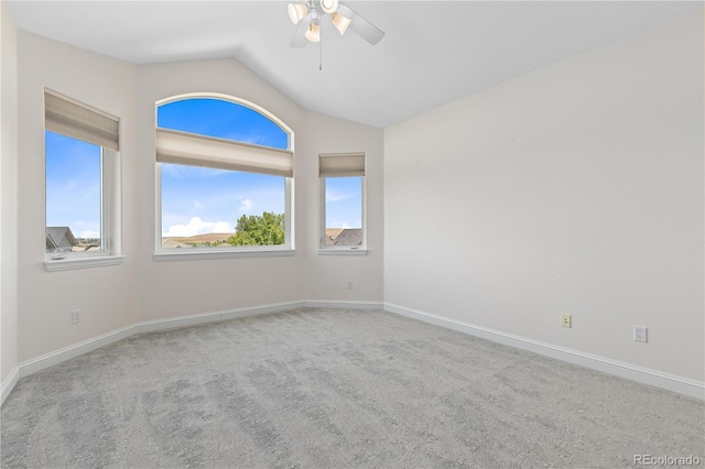 carpeted spare room featuring ceiling fan, vaulted ceiling, and baseboards