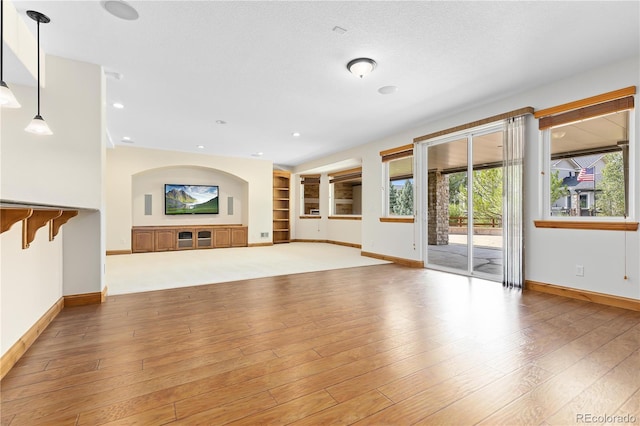 unfurnished living room with recessed lighting, baseboards, and light wood finished floors