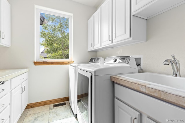 laundry area featuring a sink, visible vents, baseboards, cabinet space, and washer and clothes dryer