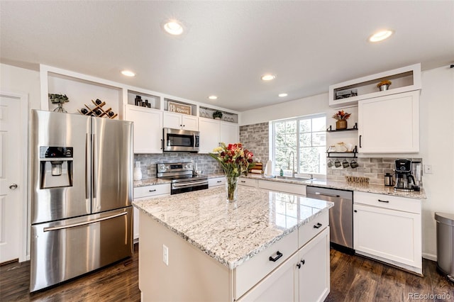 kitchen with appliances with stainless steel finishes, a kitchen island, sink, dark hardwood / wood-style floors, and white cabinetry