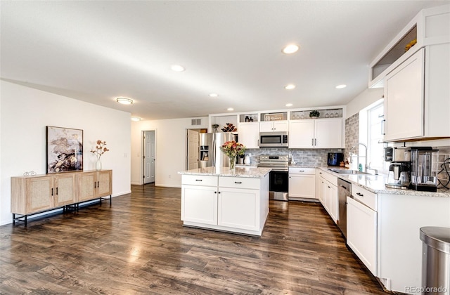 kitchen featuring appliances with stainless steel finishes, white cabinetry, a kitchen island, and sink