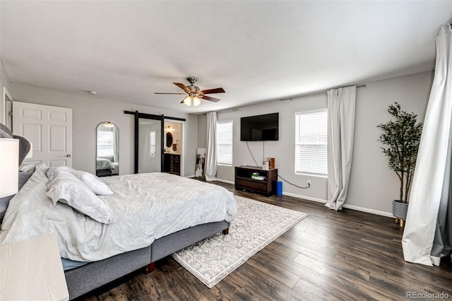 bedroom featuring a barn door, ceiling fan, ensuite bathroom, and dark hardwood / wood-style floors