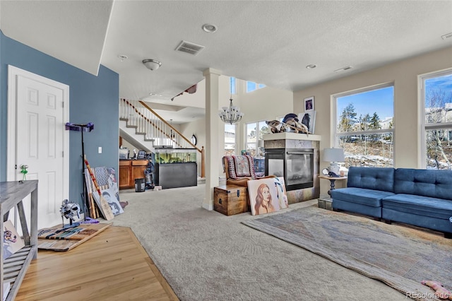 living room with a chandelier, a healthy amount of sunlight, a fireplace, and stairs