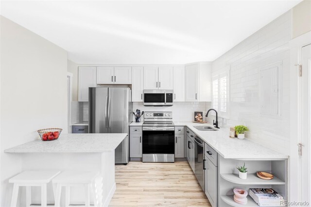 kitchen with appliances with stainless steel finishes, decorative backsplash, a sink, and gray cabinetry