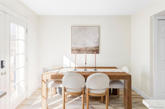 dining space featuring light wood-type flooring and baseboards