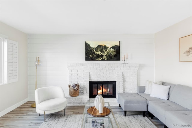 living room with a fireplace, baseboards, and wood finished floors