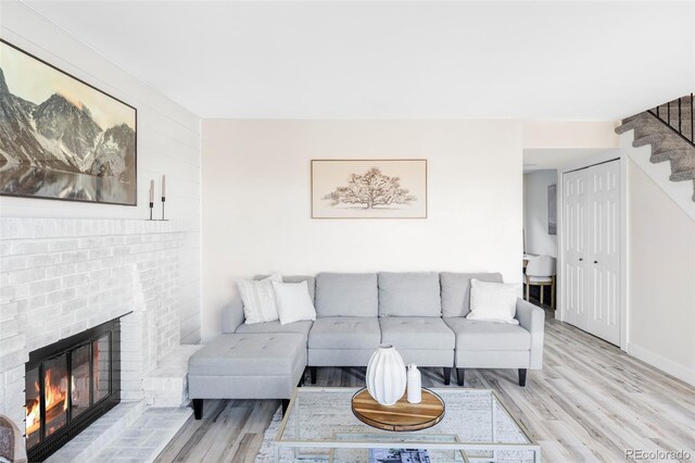 living room with a fireplace, stairway, baseboards, and wood finished floors