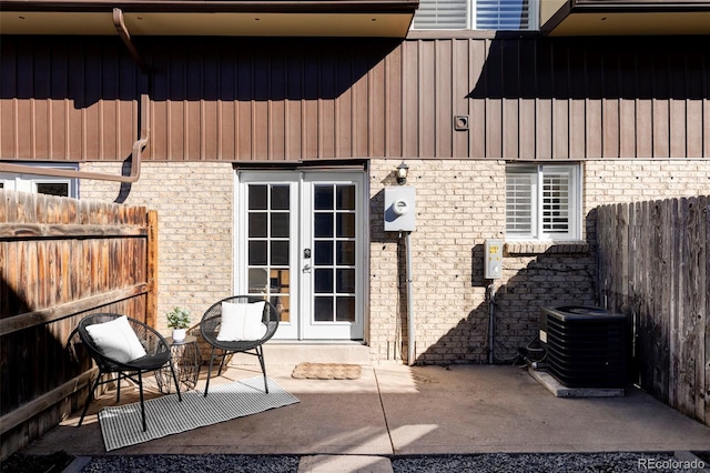 view of exterior entry with a patio area, french doors, central AC unit, and fence