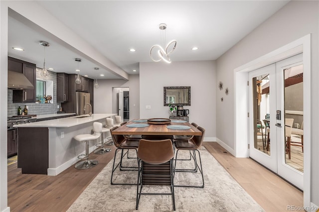 dining space featuring french doors, light hardwood / wood-style floors, and sink