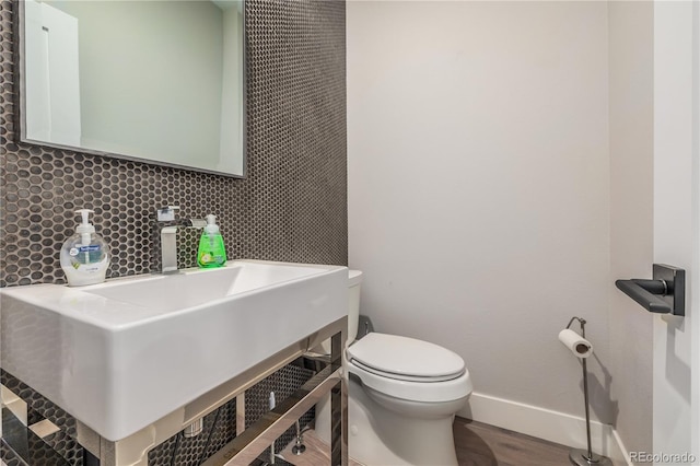 bathroom with tasteful backsplash, wood-type flooring, and toilet