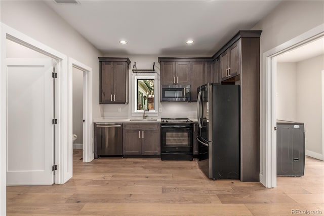 kitchen with appliances with stainless steel finishes, dark brown cabinetry, light hardwood / wood-style floors, and sink