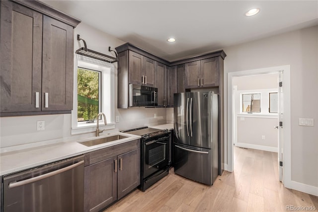 kitchen featuring dark brown cabinetry, sink, black appliances, and light hardwood / wood-style flooring