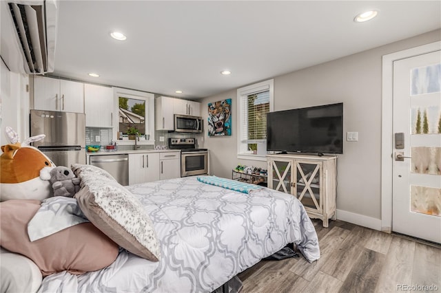 bedroom featuring light hardwood / wood-style floors, stainless steel refrigerator, and sink