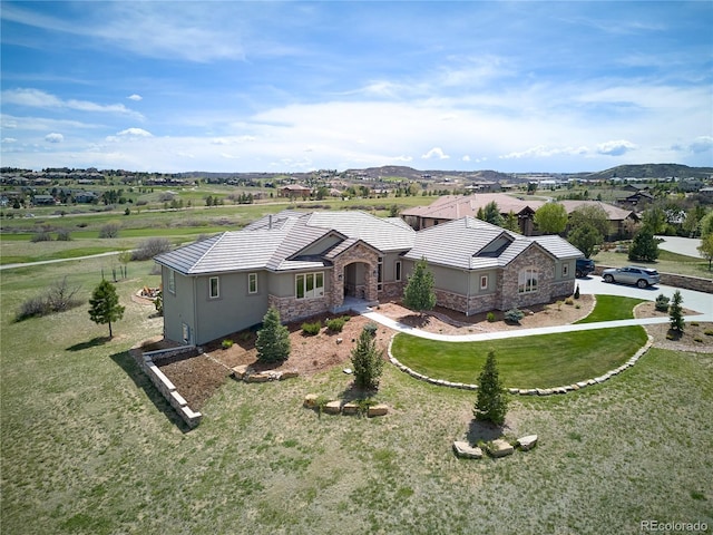 view of front facade with stone siding, stucco siding, a front yard, and a tiled roof