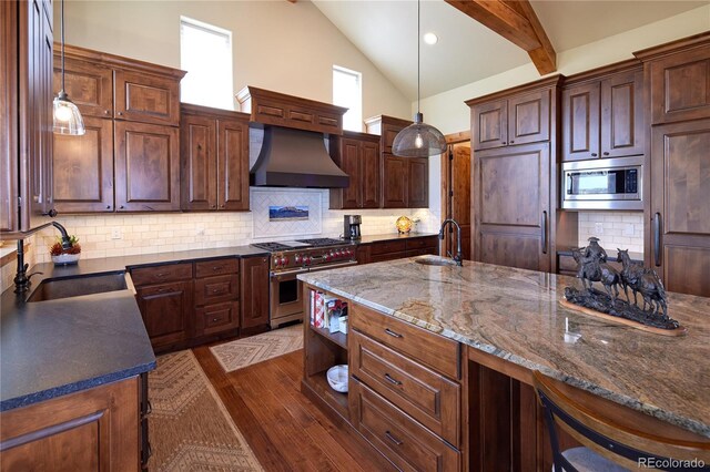kitchen featuring appliances with stainless steel finishes, a sink, wall chimney exhaust hood, dark wood finished floors, and beam ceiling