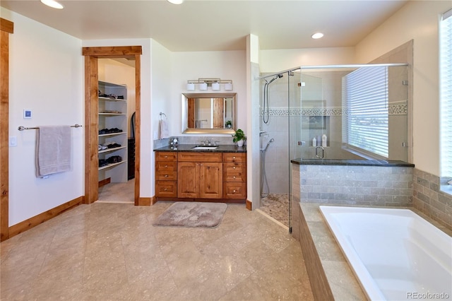 full bath with a stall shower, vanity, a bath, a spacious closet, and recessed lighting