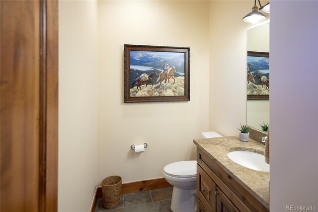 bathroom featuring toilet, baseboards, and vanity