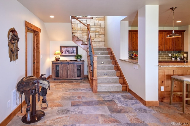 stairway featuring baseboards, stone finish floors, and recessed lighting