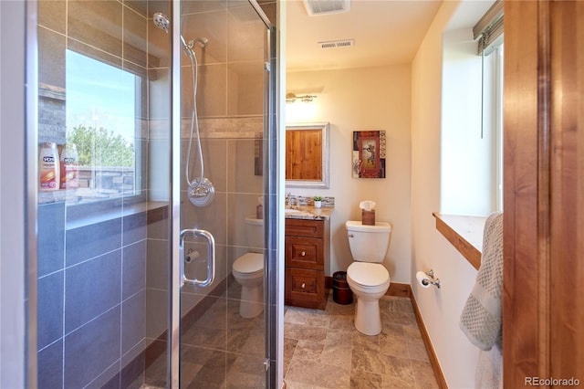 full bath featuring toilet, vanity, a shower stall, and baseboards