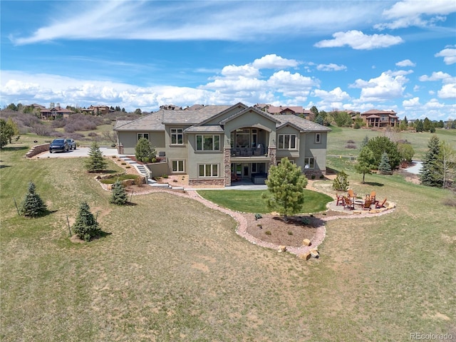 rear view of property featuring an outdoor fire pit, stucco siding, a patio, a balcony, and a yard