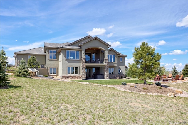 rear view of property featuring stucco siding, a balcony, a yard, and stone siding