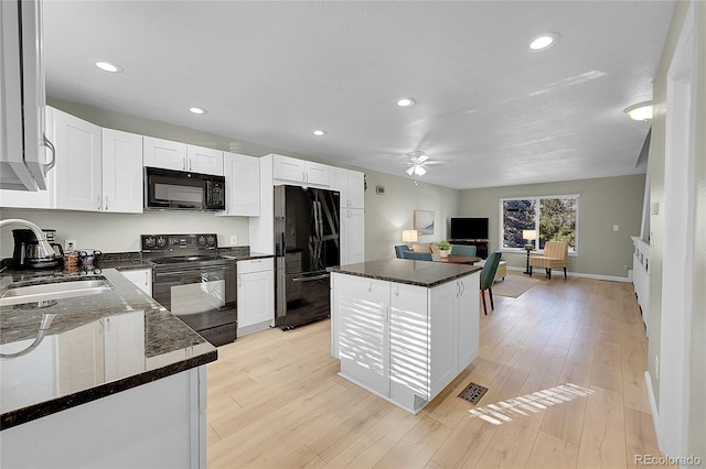 kitchen with a kitchen island, sink, white cabinets, light hardwood / wood-style floors, and black appliances