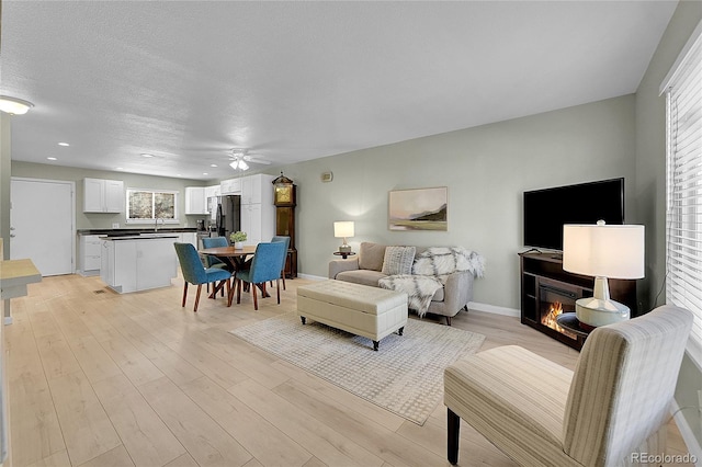 living room featuring sink, light hardwood / wood-style floors, and a textured ceiling