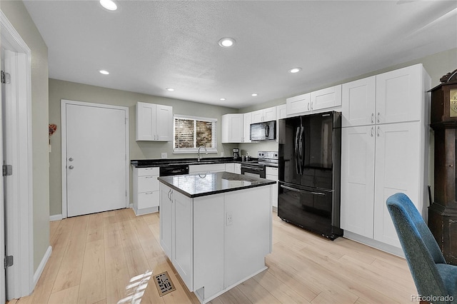 kitchen featuring black fridge, stainless steel electric range oven, a center island, light hardwood / wood-style floors, and white cabinets