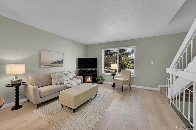 living room with a textured ceiling and light wood-type flooring