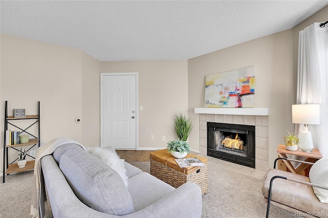 living area featuring a tile fireplace, baseboards, and a textured ceiling