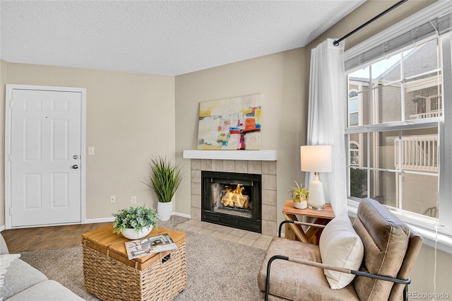 living room with baseboards, a textured ceiling, and a tile fireplace