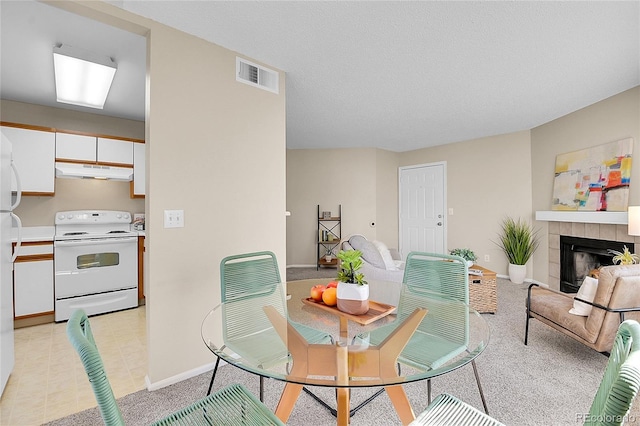 dining area with light tile patterned floors, a tile fireplace, baseboards, and visible vents