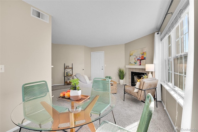 dining area with a fireplace, visible vents, carpet, and plenty of natural light