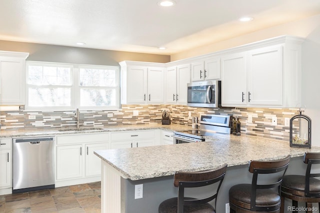 16102 Grebe Pl, Parker, CO 80134 - kitchen with appliances with stainless steel finishes, a sink, white cabinetry, a peninsula, and recessed lighting