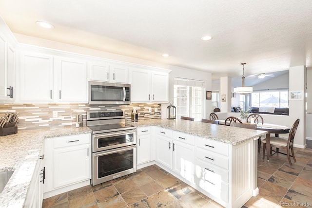 16102 Grebe Pl, Parker, CO 80134 - kitchen featuring stainless steel appliances, a peninsula, tasteful backsplash, white cabinetry, and recessed lighting